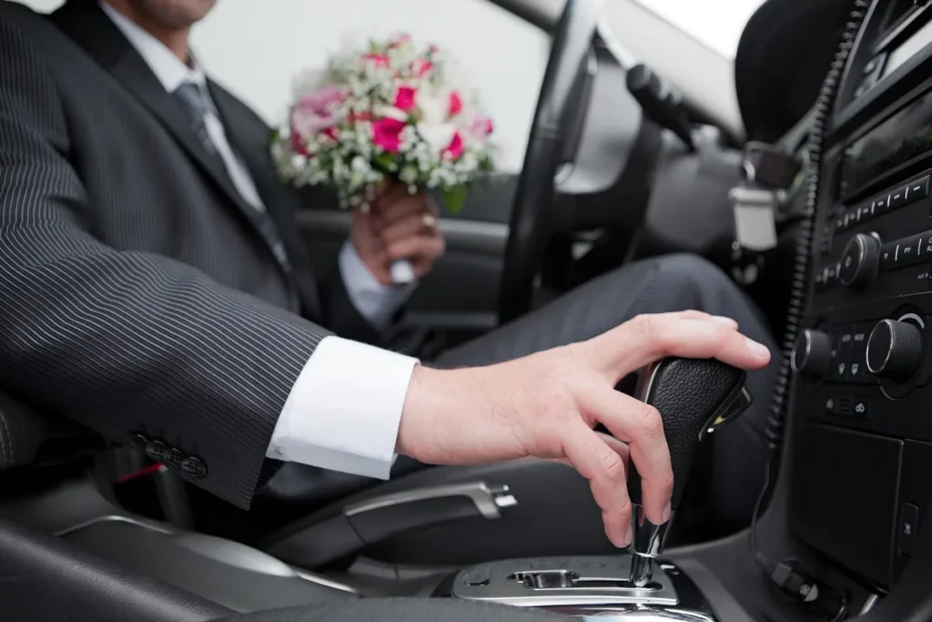 Main d’un chauffeur en costume sur le volant d’une voiture